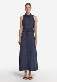 Ärmlös, marinblå linniklänning med knappstängning, krage och knytdetalj i midjan. Maxilängd med en mjuk textur och en flödande silhuett.