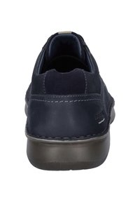 Scarpe in pelle blu navy con retro arrotondato, cuciture a contrasto e suola in gomma testurizzata. Design minimalista senza loghi visibili.