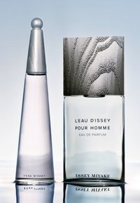 Deux flacons de parfum : un flacon haut, mince, en verre transparent avec un capuchon en argent ; l'autre flacon est carré, en verre dépoli avec un dessus en argent texturé.