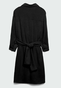 Robe noire en tissu texturé. Présente un col, des manches longues et une ceinture nouée à la taille. Design simple et minimaliste.