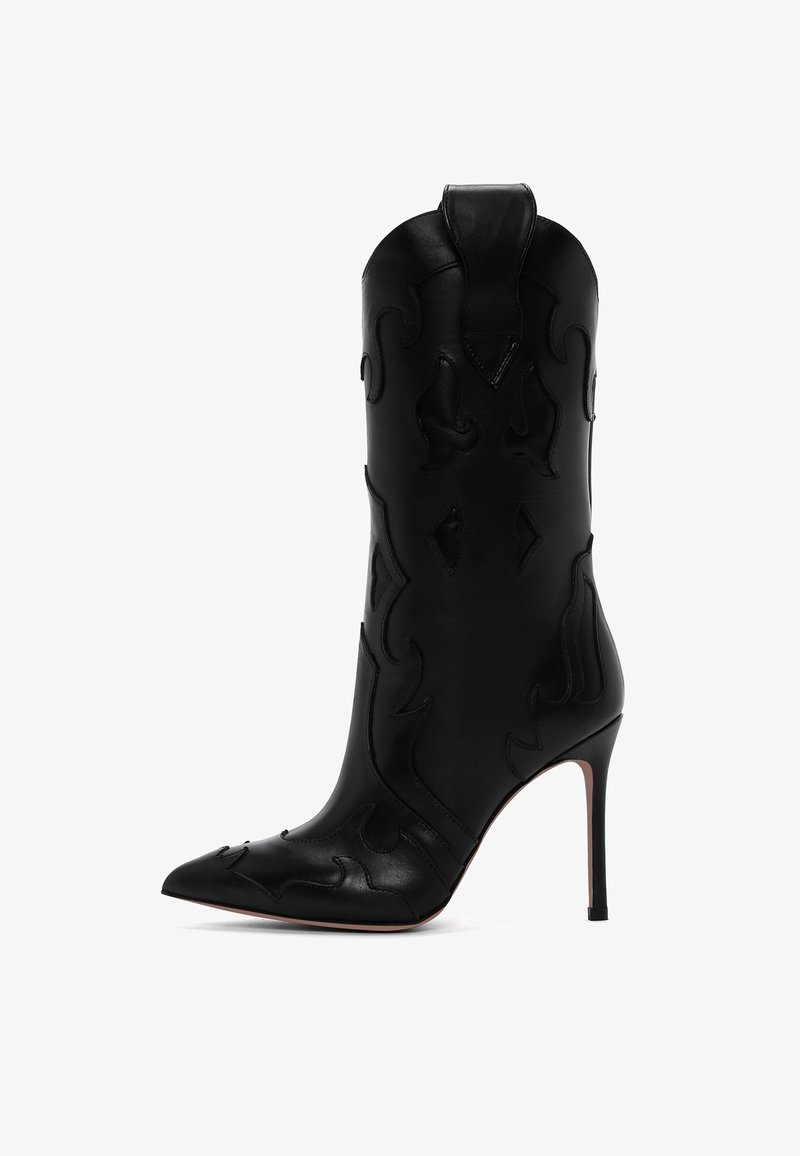 Stivale alto in pelle nera con punta affilata e motivi decorativi intagliati, caratterizzato da una silhouette aderente e un tacco a stiletto.