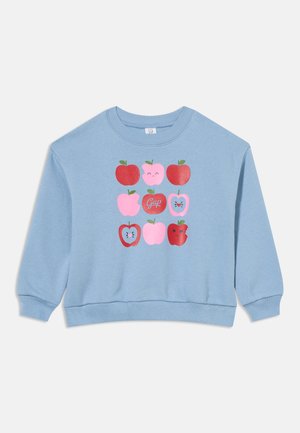 Sweat-shirt bleu clair avec une grille de pommes rouges et roses, certaines avec des visages, une avec le mot "Gap" dans la pomme centrale.