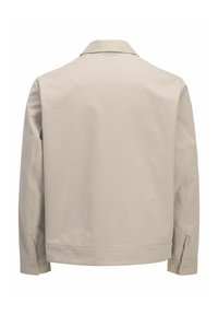 Ανοιχτό μπεζ υφασμάτινο μπουφάν με μακριά μανίκια, γιακά και κουμπωτά μανίκια, εμφανιζόμενο από πίσω σε λευκό φόντο.