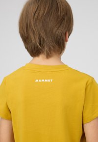 Geel T-shirt met korte mouwen gemaakt van katoen. Kenmerkt zich door een ronde hals en een wit 'MAMMUT' logo dat op de achterkant is gedrukt. Glad textuur.