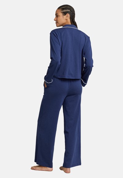 Set de pijamale bleu marin cu o croială lejeră, având o jachetă cu guler și mâneci lungi, completat de o pereche de pantaloni largi cu buzunare laterale.
