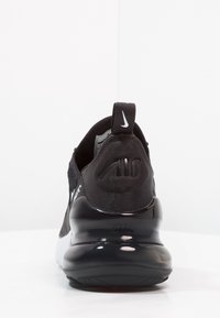 Black sneaker featuring a textured mesh upper, padded collar, prominent rear heel cap, and a glossy black air sole. Nike logo on heel.