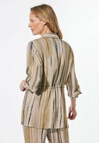 Lichte, lange mouwen blouse in beige met verticale strepen in groen en bruin. Heeft een cinched taille en opgerolde manchetten voor een relaxte pasvorm.