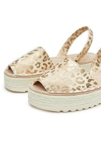 Sandalias de estampado de leopardo con acentos metálicos dorados, diseño de punta abierta y suela de yute trenzada. Parte superior de suave color beige con correas elásticas.