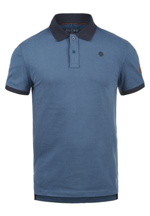 Polo en coton bleu avec un col et des poignets de manches navy. Présente une patte de boutonnage et un logo sur la poitrine. Texture lisse.