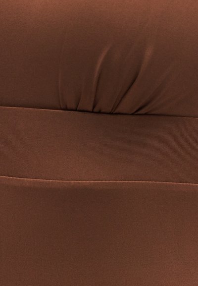 Κοντινό πλάνο καφέ υφάσματος με ελαστική ταινία και ριγωτή ραφή σε λεία υφή επιφάνειας.