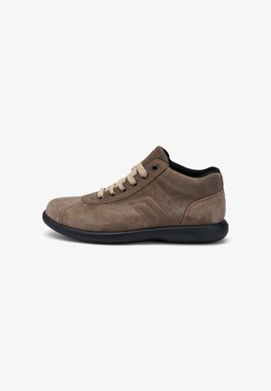 Zapato de ante marrón con puntera redondeada, suela de goma negra contrastante, cordones crema y un sutil detalle lateral. Textura suave y diseño de perfil bajo.