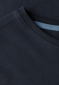 Tmavě modré tričko s žebrovaným kulatým výstřihem a hladkým povrchem, s kontrastním světle modrým štítkem uvnitř límce.