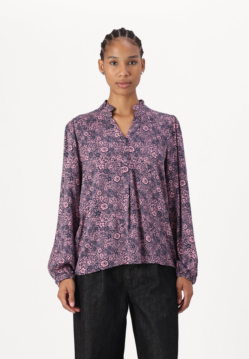 Blusa floreale viola con scollatura arricciata, maniche lunghe e vestibilità comoda; il tessuto presenta un motivo di piccoli fiori e swirl.