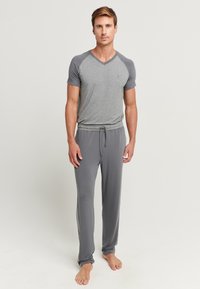 Grijze T-shirt met korte mouwen en V-hals, met donkere grijze accenten, gecombineerd met grijze jogpants met koord. Zachte, lichte stof.