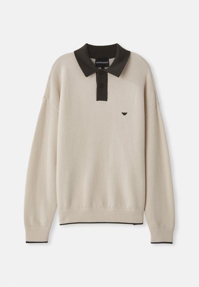 Langermet beige genser med svart krage og knappestolpe, svart logo på brystet, ribbede mansjetter og ribbestrikket kant med svart trim.