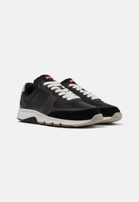 Czarno-szare sportowe sneakersy z połączeniem materiałów skórzanych i zamszowych, białymi sznurowadłami i teksturowaną gumową podeszwą.