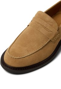 Zamszowe mokasyny w kolorze koniakowym z wzorem mokasyna, ozdobnym przeszyciem, gładką skórzaną wyściółką i kontrastową gumową podeszwą.