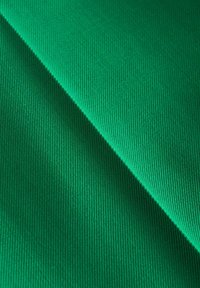 Groen textielmateriaal met een gladde, geribbelde textuur, met diagonale plooien die de levendige kleur en het uniforme oppervlak benadrukken.