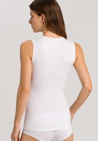 White sleeveless top made of smooth, stretchy fabric. Fitted design, slightly rounded neckline, minimal seams, and no visible detailing on the back.