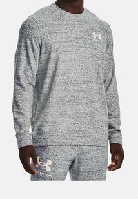 Camisa de manga larga gris claro hecha de tejido texturizado, con cuello redondo y un discreto logo de Under Armour en el pecho.