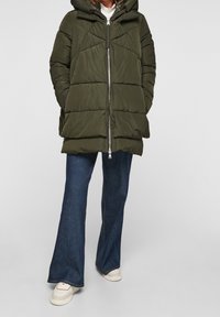 Chaqueta acolchada en verde oliva, con capucha, que presenta acolchado horizontal, cierre de cremallera, bolsillos laterales y un acabado texturizado.