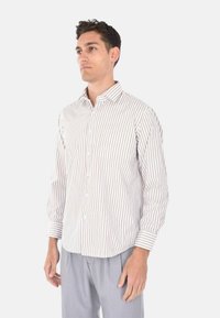 Camicia a maniche lunghe con bottoni, righe verticali beige e bianche, colletto a punta, taschino frontale e polsini con bottoni.