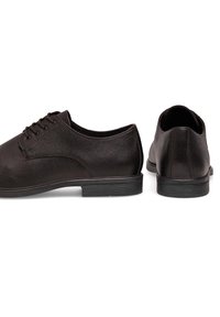 Mustad mustad nahast jalanõud, millel on tekstureeritud viimistlus, ümardatud varvas, lipsudega disain ja madal kummitald. Tagantvaates on nähtav õmblusdetail.