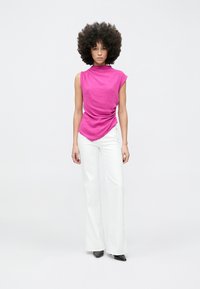 Fuchsia mouwloze top met gedrapeerd detail, gecombineerd met witte uitlopende broek en zwarte puntige schoenen, met een gladde textuur en strakke pasvorm.