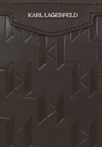 Brązowy skórzany portfel z wytłoczonym wzorem logo, zapięciem na zatrzask i srebrnymi akcentami z brandingiem "KARL LAGERFELD".