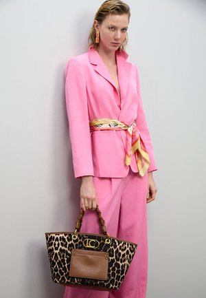 Conjunto de blazer y pantalones color rosa brillante, combinado con un bolso tote de estampado de leopardo con un detalle de cuero marrón y asa tejida.