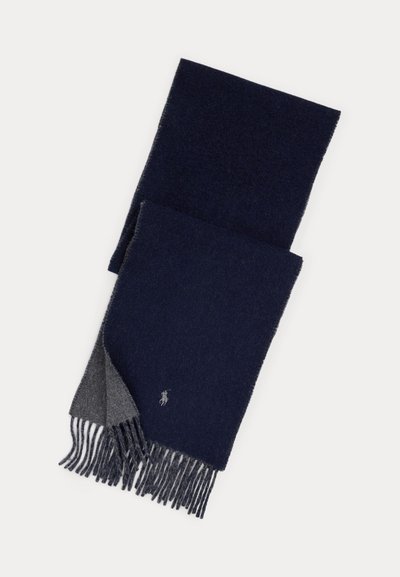 Donkerblauwe en grijze wollen sjaal met franjes aan de uiteinden en een klein geborduurd logo aan één kant, getoond opgevouwen tegen een witte achtergrond.