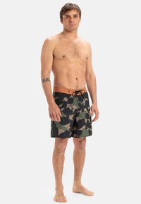 Schwarze und grüne Camouflage-Badehose mit einem orangen Taillenbund, Kordelzug und einem leichten Stoff; knielanger Schnitt mit lockerer Passform.