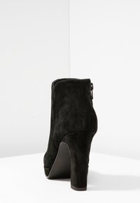 Bottines en suede noir avec un talon haut, présentant une finition lisse, une fermeture éclair latérale et un design à bout rond.