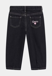 Schwarze Jeans mit geradem Schnitt, mit pinken Nähten und "Guess"-Logo mit einem Herz auf der rechten Gesäßtasche.