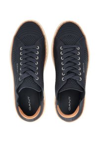 Granatowe plecione sneakersy z fakturowanym wierzchem, okrągłym noskiem, sześcioma oczkami i jasną gumową podeszwą. Logo marki widoczne z boku.