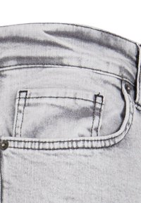 Heledad hallid denim püksid, millel on nähtav tagatasku, õmblustega äärised ja metallist nupukesed. Pehme tekstuur ja kerge pleekimine.