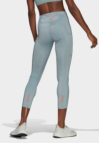 Legginsy wykonane z jasnoniebieskiej elastycznej tkaniny, z kieszenią na zamek z tyłu, z różowymi zygzakowymi akcentami na dolnych nogawkach.