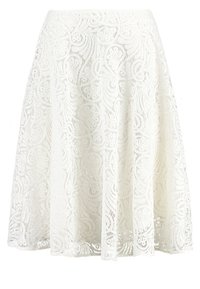 Weißer Spitzenrock mit wirbelndem Muster und wellenförmigem Saum. Ausgestelltes Design mit filigranen Details und leichtem Stoff.