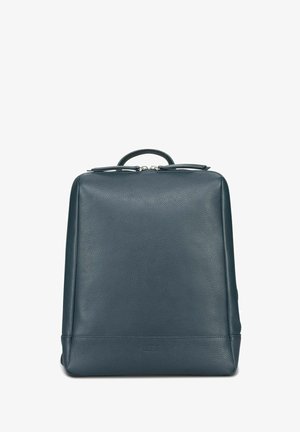 Sac à dos en cuir bleu foncé de forme rectangulaire, texture lisse, poignée supérieure, et quincaillerie argentée pour la fermeture éclair. Design minimaliste.