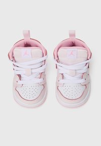 Para małych różowych i białych sneakersów dla niemowląt z białymi sznurówkami i różowym logo Jumpman na języku, widziane z góry.