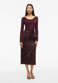 Bordeaux langemouwtop met een cadeautje halslijn en een bijpassende pailletten midi rok; gladde textuur bovenop, glinsterend oppervlak op de rok.