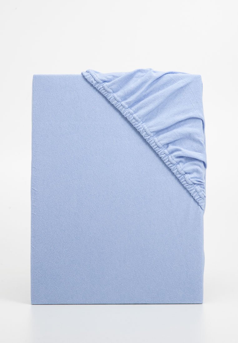 Sábana ajustable azul hecha de un tejido suave, con un borde fruncido en una esquina para un ajuste seguro. Textura suave, color uniforme.