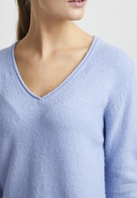 Pullover a scollo a V blu chiaro con un morbido tessuto a maglia testurizzata; presenta maniche lunghe e una vestibilità comoda per uno stile casual.
