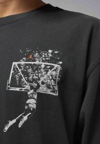 Black cotton sweatshirt featuring a graphic print of a player dunking a basketball, with a shattered backboard and an orange logo detail.