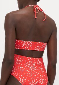 Rode bloemen bikini set met een bandeau top met verstelbare halterstrik en hoog getailleerde broekjes, met een klein wit bloemenpatroon.