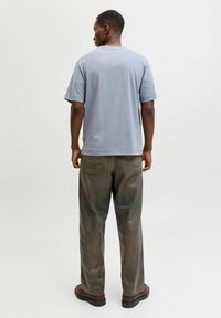 Hall roheline l�ühikeste varrukatega t-särk ringkaelusega, millele on kombineeritud laiad tumedad rohelised teksad. Komplekti kuuluvad tumepruunid botased sileda pinnaga.