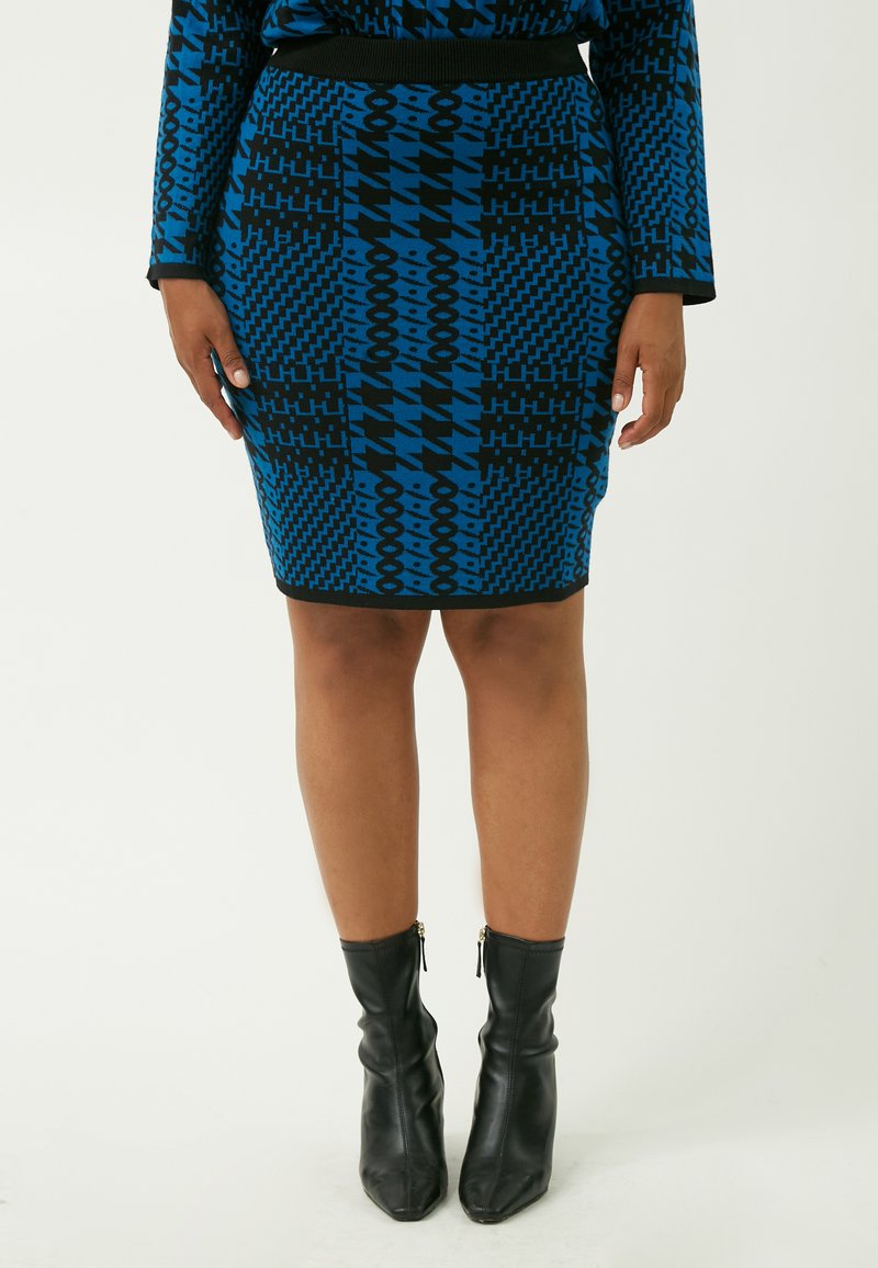 Falda de punto con estampado azul que presenta diseños geométricos en negro. Acompañada de botas negras hasta el tobillo con cremalleras y un acabado suave.