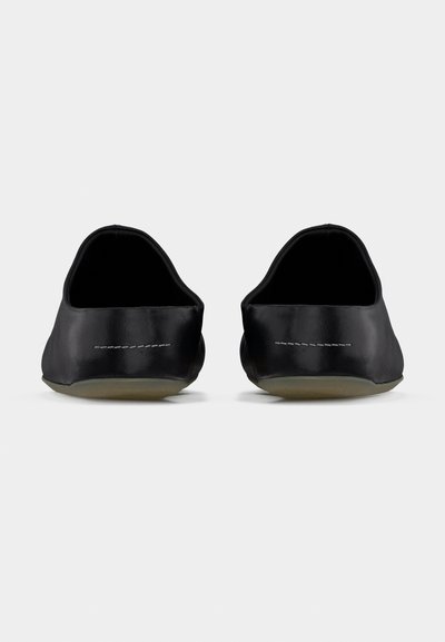 Μαύρα παπούτσια slip-on με ματ, λεία επιφάνε ια, χαμηλό προφίλ σχεδίασης και διακριτικές λευκές ραφές. Στρογγυλεμένες φτέρνες και ευέλικτες σόλες.