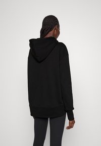 Felpa nera con cappuccio e vestibilità rilassata, polsini e vita a coste. Tessuto liscio, colore uniforme e dettagli di cucitura visibili.