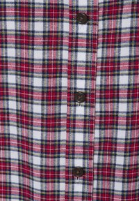 Camicia a quadri rossa, blu, gialla e bianca con bottoni neri, caratterizzata da un motivo di linee incrociate e un tessuto morbido e texturizzato.